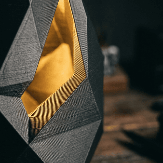 Close-up macro shot of 3D printed layers on a geometric lamp, warm gold light catching the fine layer lines